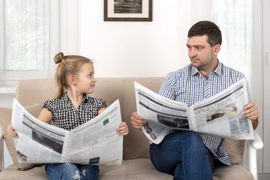 Girl copying dad reading the newspaper